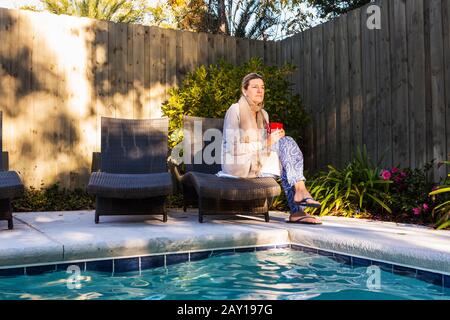 Frau, die auf einer Sonnenliege am Pool sitzt Stockfoto