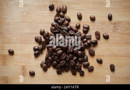 Dunkel geröstete Kaffeebohnen befinden sich auf einem Holzschreibtisch. Flaches Lay, Foto in der Draufsicht Stockfoto