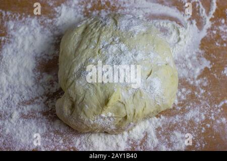 Teigkugel auf dem Tisch mit Mehl bestreut. Teig zum Backen von Desserts oder Pizza. Stockfoto