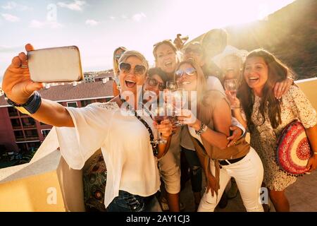 Gruppe fröhlicher und fröhlicher junger Frauen haben Spaß bei der Party zusammen im Freien und machen selfie-fotos mit dem Telefon - die Leute feiern mit Wein und Toasting Stockfoto