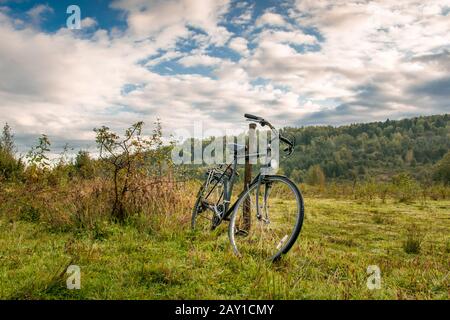 Ein altes Fahrrad, das von jemandem aufbewahrt und vergessen wird und morgendliche Abgaben vor dem Hintergrund des schönen Siebenbürgischen Waldes sammelt. Stockfoto