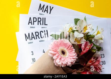 Kalender für Frühlingsmonate. März, April und Mai monatliche Papierkalender mit einem Blumenstrauß aus Frühlingsblumen. Draufsicht. Ansicht von oben. Federhintergrund Stockfoto