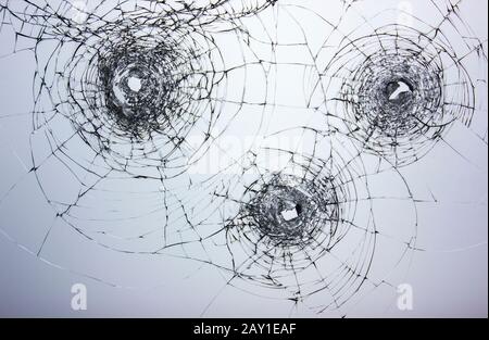 Risse an zerbrochenem Glas nach Schusswaffen. Vandalismus und Angriff mit einer Schusswaffe. Beschädigte Fensterräuber. Stockfoto