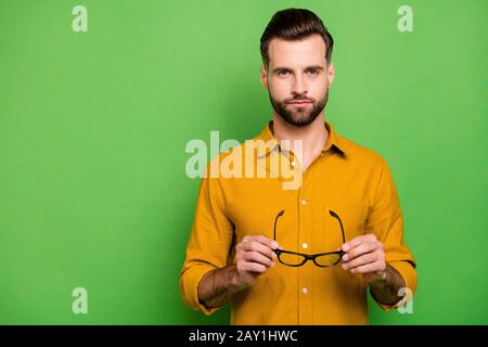 Nahaufnahme seines hübschen, ernsten bärtigen, bärtigen, bärtigen Mannes in einem lässigen, formellen Hemd, das in den Händen hält, sprießlich isoliert auf hell lebhaft Stockfoto