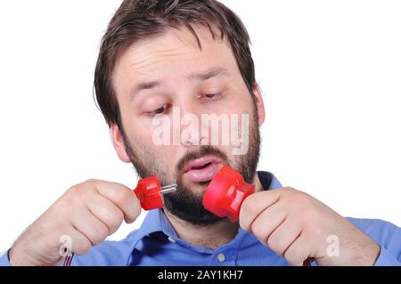 Junger Mann mit überraschtem Gesicht, der mit Elektrizität zu tun hat Stockfoto