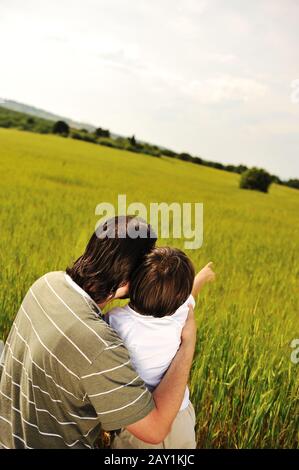 Porträt eines jungen Jungen, der etwas mit seinem Vater gegen die natürliche Szene interstiert Stockfoto