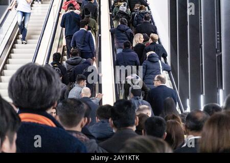 Menschen, die während der Coronovirus-Pandemie auf einer internationalen Messe für Rolltreppen Schlange stehen, einige von ihnen tragen Maske, um sie zu schützen Stockfoto