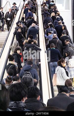 Menschen, die während der Coronovirus-Pandemie auf einer internationalen Messe für Rolltreppen Schlange stehen, einige von ihnen tragen Maske, um sie zu schützen Stockfoto