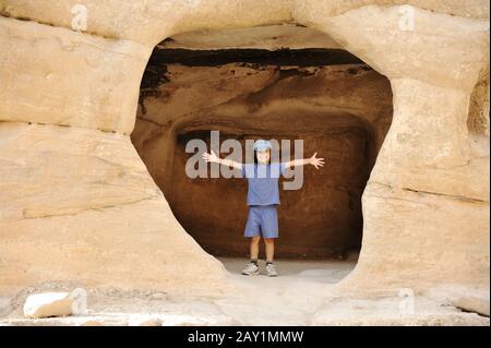 Tourist Kind posiert im Felsloch, glückliches Kind mit einer Kappe Stockfoto