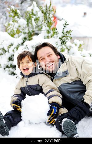 Vater und Sohn spielen glücklich im Schnee Schneemann, Wintersaison Stockfoto