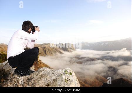 Junger professioneller Mann mit Kamera, die im Freien fotografieren kann, fantastische Landschaft Stockfoto