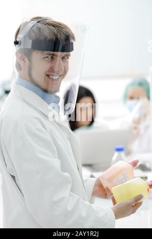Junger medizinischer Arbeiter mit Glasmaske, der mit seinem Team im Labor zusammenarbeitet Stockfoto