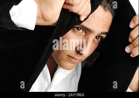 Porträt eines ernsthaften jungen Mannes, der mit seiner Jacke Kopftuch macht Stockfoto