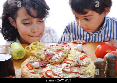 Zwei Kinder mit überraschtem Gesicht auf dem Pizza-Tisch Stockfoto