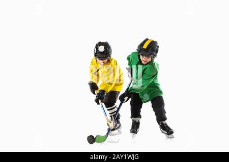 Kleine Eishockeyspieler mit den Stöcken auf dem Eisplatz und weißem Studiohintergrund. Sportsboys tragen Ausrüstung und Helmübung. Sportkonzept, gesunder Lebensstil, Bewegung, Bewegung, Action. Stockfoto