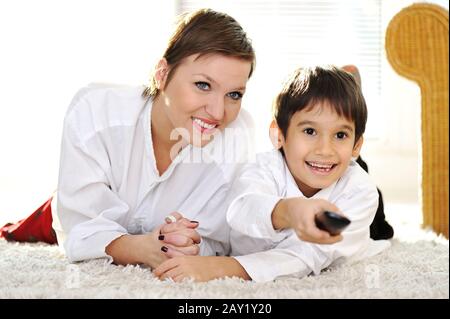 Mutter mit Sohn auf dem Boden liegend und Fernsehen über Fernbedienung Stockfoto
