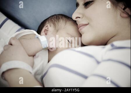 Frau, die ihr neugeborenes Baby im Krankenhaus hält Stockfoto