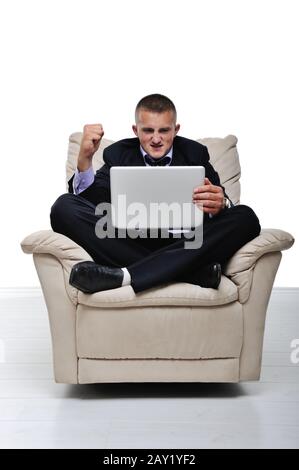 Der junge Mann war überrascht und glücklich über etwas, das er auf seinem Laptop sieht Stockfoto