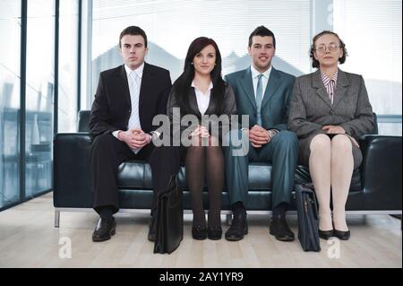 Vier Geschäftsleute sitzen hintereinander auf dem Sofa Stockfoto