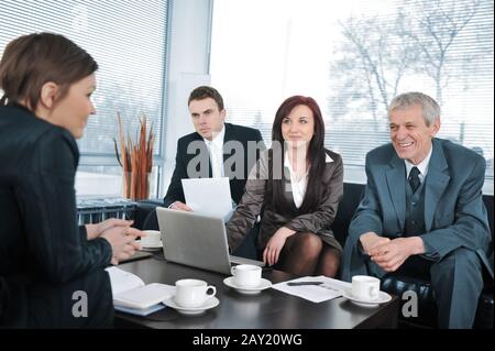 Geschäftsfrau in einem Interview mit drei Geschäftsleuten, die positives Feedback erhalten Stockfoto
