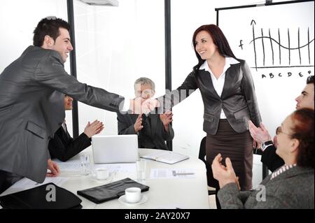 Geschäftspartner schütteln die Hände, nachdem sie Geschäfte gemacht haben, während ihre Mitarbeiter applaudieren Stockfoto