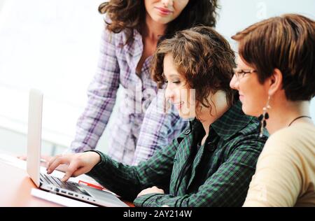 Gruppe junger glücklicher Menschen, die ein Notebook suchen, das daran arbeitet Stockfoto