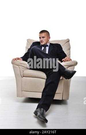 Geschäftsmann, der im Sessel sitzt und die Beine isoliert gekreuzt hat Stockfoto