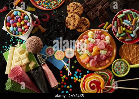 Eine Auswahl an Party-Leckereien für einen Kindergeburtstag mit verschiedenen Süßigkeiten, Eis, Plätzchen, Keksen, Schokoladenriegeln, Einstreuern und Lollipops in einem Over Stockfoto