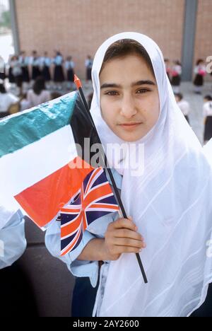 Ein Mädchen wartet mit ihren Fahnen, um TRH Prince und Princess of Wales 1989 in Kuwait willkommen zu heißen. Stockfoto