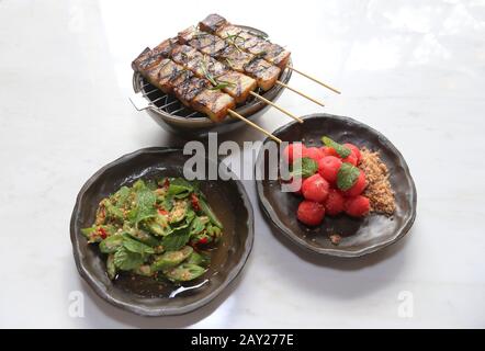 Thai-Food zeichnet sich durch leicht zubereitete Gerichte mit starken aromatischen Komponenten und einem würzigen Rand aus. Es gibt Satay, Okra und Wassermelone. Stockfoto