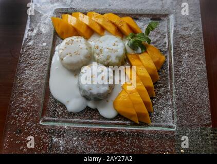 Thailändischer Haferreis mit Mango mit Kokosnusssoße. hai-Gerichte zeichnen sich durch leicht zubereitete Gerichte mit starken aromatischen Komponenten und einer würzigen Kante aus. Stockfoto