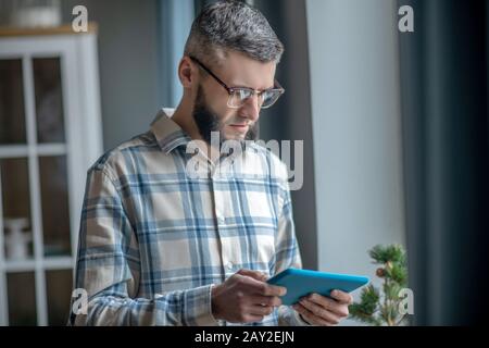 Junger Mann in Brille mit Tablette in den Händen. Stockfoto