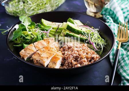 Mittagssalat. Buddhaschüssel mit Buchweizenporridge, gegrilltem Hühnerfilet, Maissalat, Mikrogrüns und Daikon. Gesunde Ernährung. Stockfoto