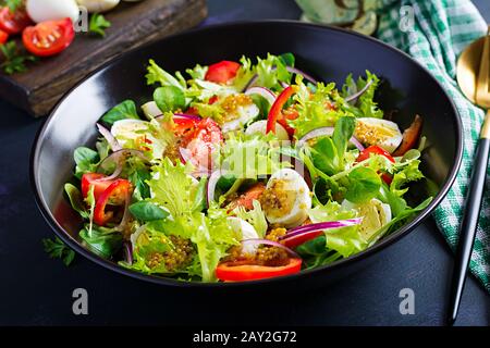 Frischer Salat mit Gemüse Tomaten, roten Zwiebeln, Salat und Wachteleiern. Gesundes Lebensmittel- und Diätkonzept. Vegetarisches Essen. Stockfoto