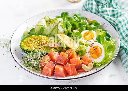 Ketogenes Diät-Frühstück. Salat mit Salat aus Salzlachs mit Grüns, Gurken, Eiern und Avocado. Mittagskino/Paleo. Stockfoto