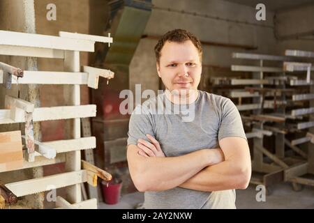Junger Mann als Tischlerpraktikant vor der Leimpresse in der Tischlerei Stockfoto