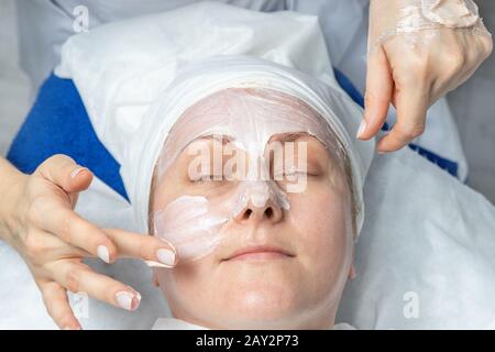 Nahaufnahme Kosmetikerin Doktor Hände, die Anti-Age-Verfahren durchführen, Gesichts- und Kopfmassage für Frauen mittleren Alters in der Schönheitsklinik. Kosmetologe Stockfoto