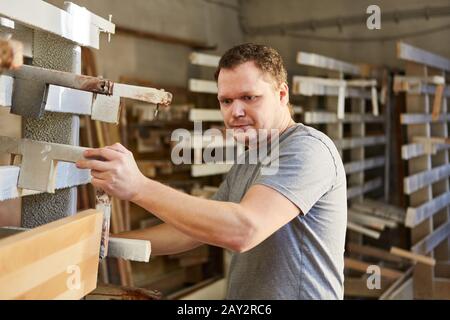 Junger Mann als Schreinerlehrling, der Holz in der Zimmermannswerkstatt verleimt Stockfoto