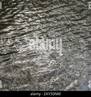 Etwas turbulentes Wasser wellt auf River Fowey, Lostwithiel, Corrnwall. Metapherapheres, luftiges Wetter, Rippeleffekt, Wasserspiegelungen, wässriger Hintergrund. Stockfoto