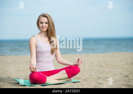 Junge Dame Yoga zu praktizieren. Training in der Nähe von Meeresküste des Ozeans. Stockfoto