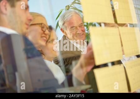 Das Business Team macht einen Workshop mit vielen Notizen an einer Glaswand Stockfoto