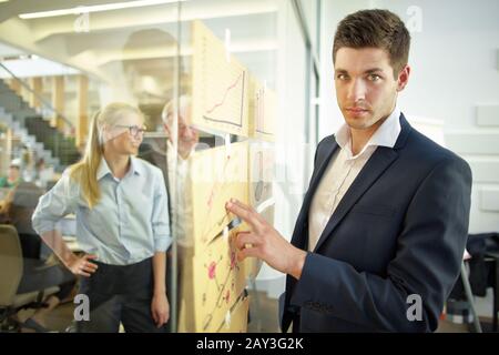 Der Geschäftsmann erstellt Analysen mit Statistiken und Diagrammen an einer Glaswand Stockfoto