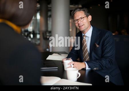 Lächelnder Geschäftsmann, der im Restaurant spricht Stockfoto
