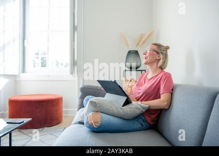 Frau auf Sofa mit digital-Tablette Stockfoto