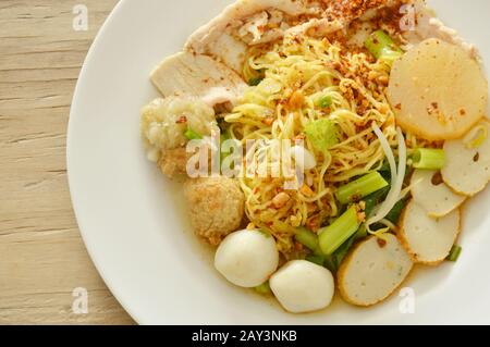 Getrocknete pikante chinesische Eiernudeln, die Fisch und Garnelenkugel mit geschliffenem gekochtem Schweinefleisch auf dem Teller überfüllen Stockfoto