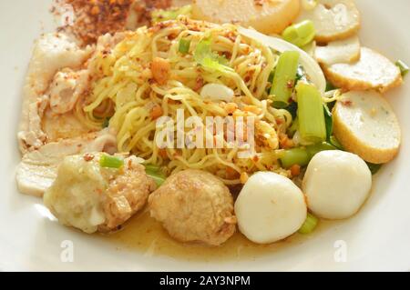 Getrocknete pikante chinesische Eiernudeln, die Fisch und Garnelenkugel mit geschliffenem gekochtem Schweinefleisch auf dem Teller überfüllen Stockfoto