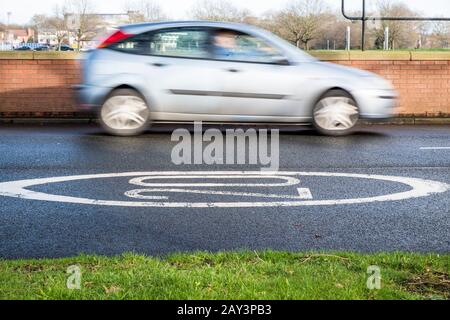 Auto, das an einem 20-km/h-Geschwindigkeitsbegrenzungszeichen vorbeifährt, auf einer Straße, Nottingham, England, Großbritannien, gemalt Stockfoto