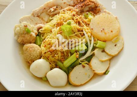 Getrocknete pikante chinesische Eiernudeln, die Fisch und Garnelenkugel mit geschliffenem gekochtem Schweinefleisch auf dem Teller überfüllen Stockfoto