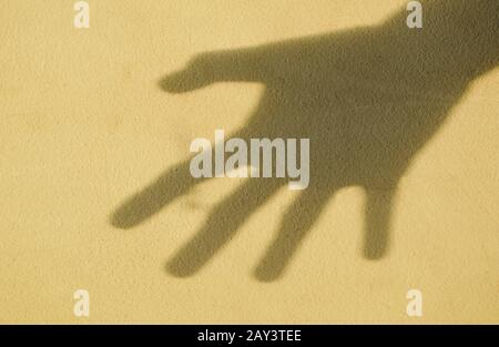 Schatten der geöffneten Hand an der alten Zementwand Stockfoto