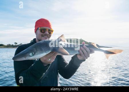 Mann auf Boot, der Fisch hält Stockfoto